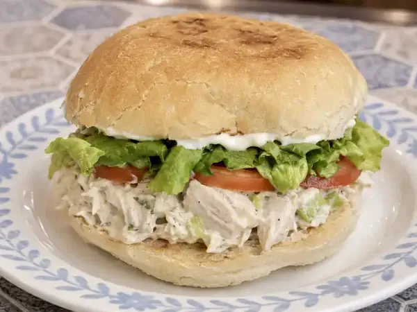 Chicken salad sandwich with lettuce and tomato on a café plate