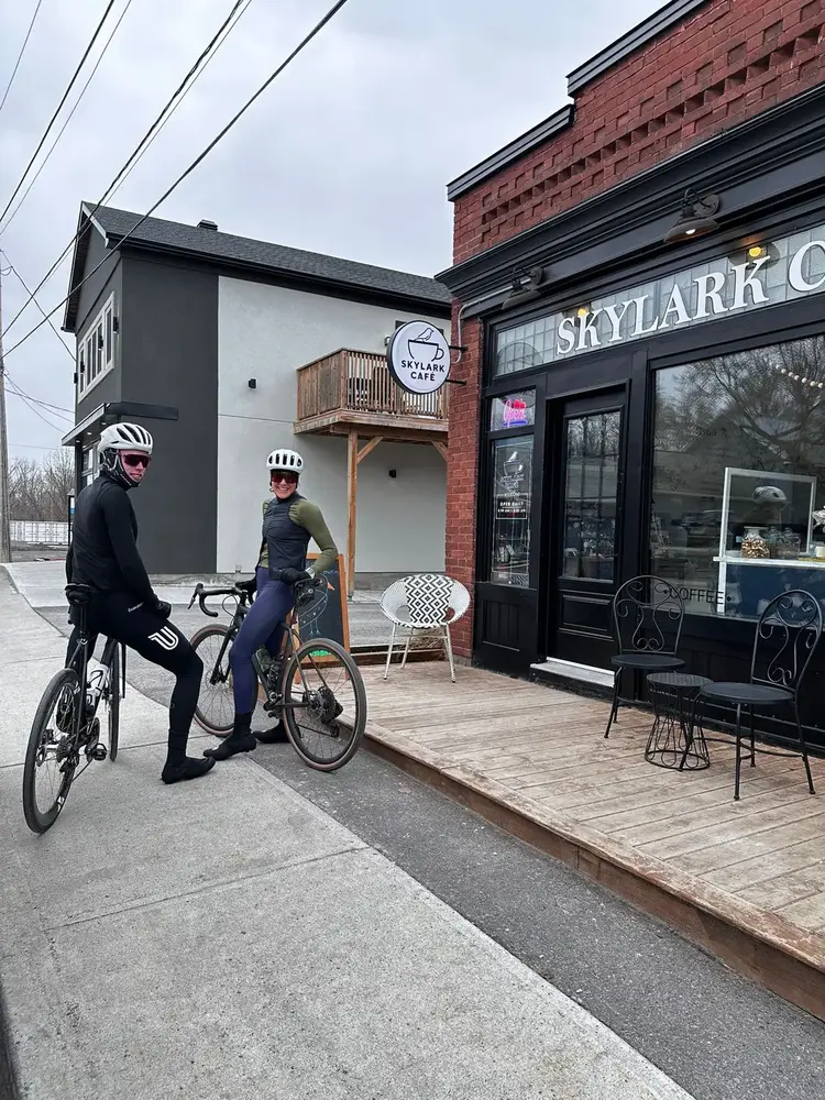 Two cyclists with their bikes beside the Skylark Café storefront