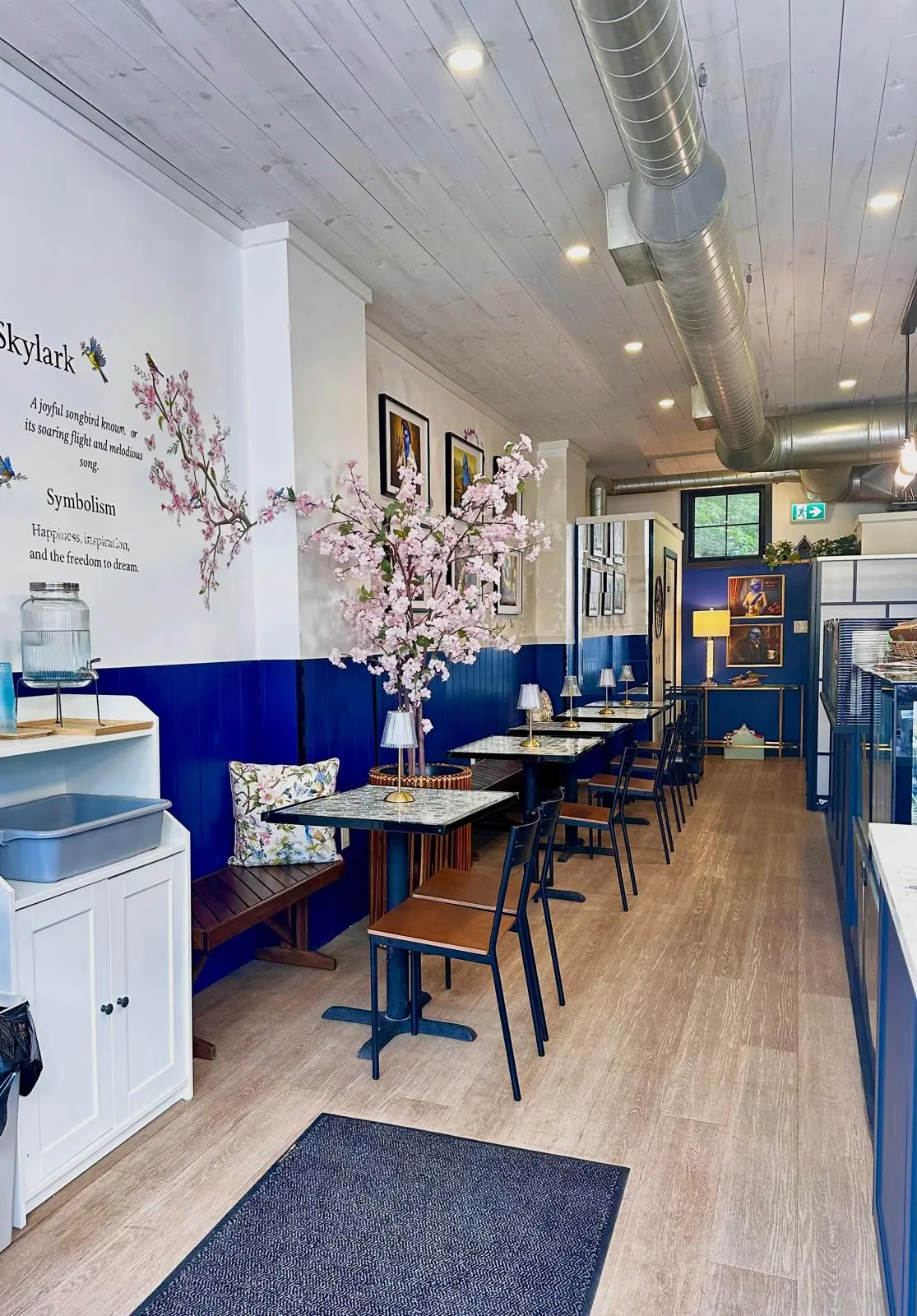 The welcoming interior of Skylark Café in Carp, with café tables, cherry blossoms and blue wall panelling