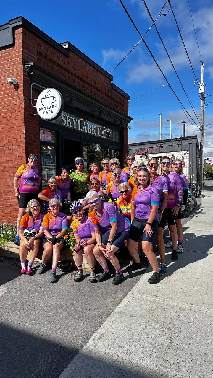 A group of cyclists in colourful jerseys gathered outside Skylark Café
