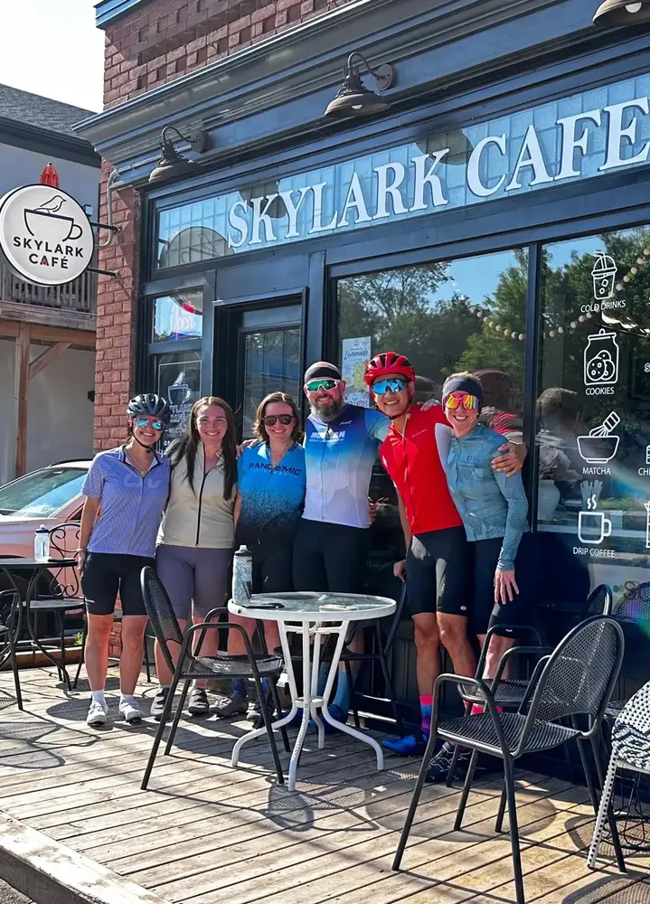 Six cyclists standing together outside Skylark Café